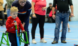 Little boy with a walking frame playing accessible cricket in a sports hall