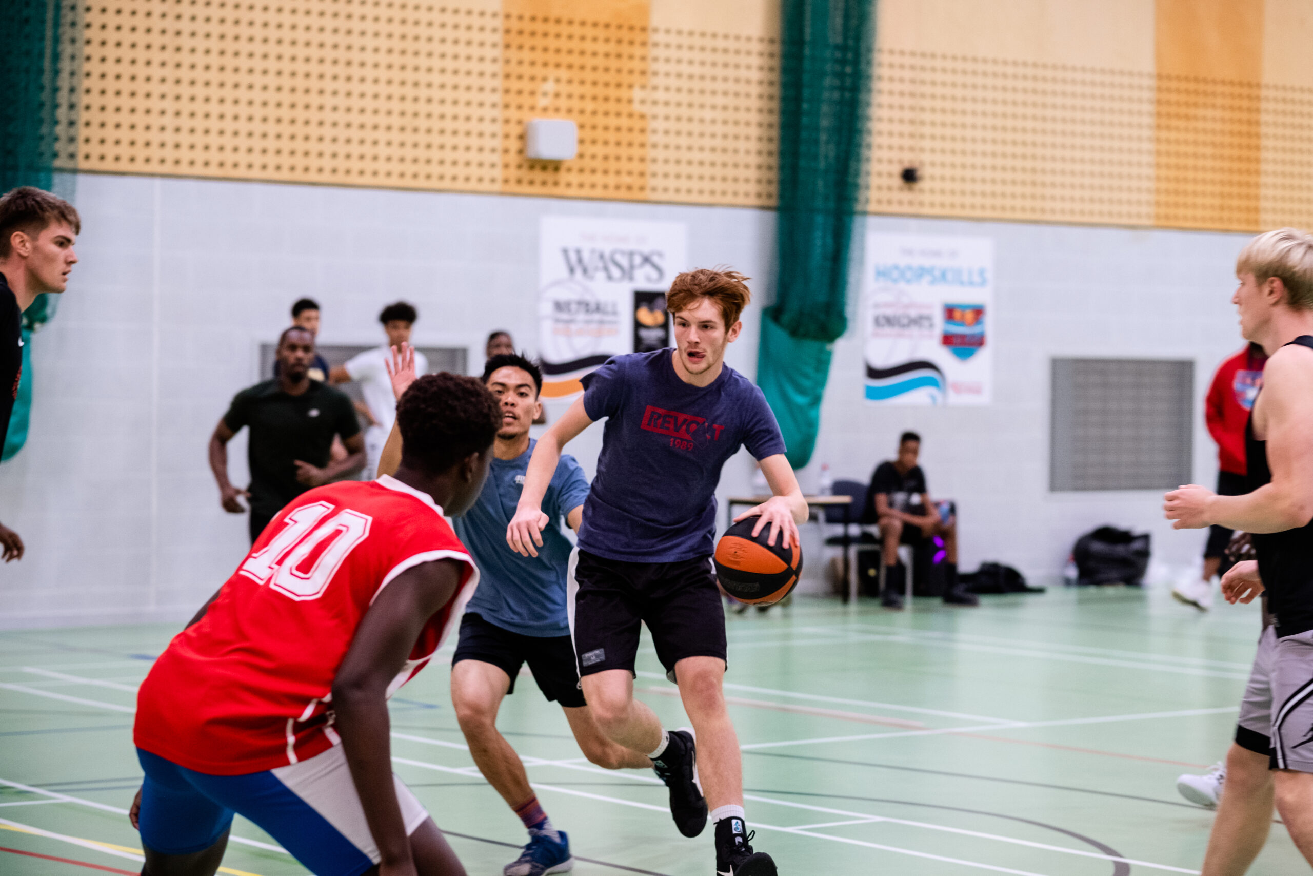 Young people playing basketball indoors.