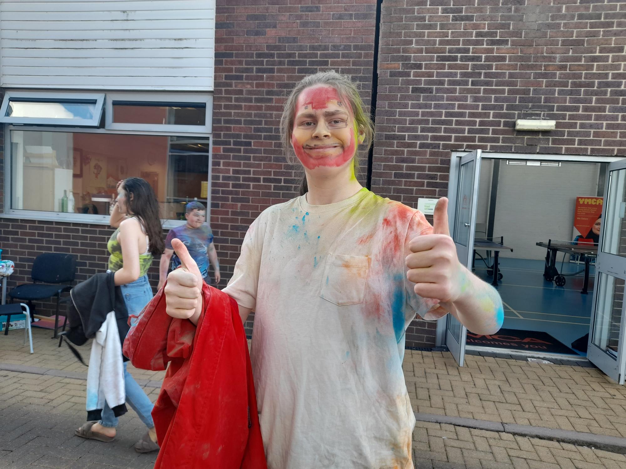 A young person holding their thumbs up.