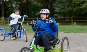 A young person with a disability cycling outdoors. (Image by Sport England.)