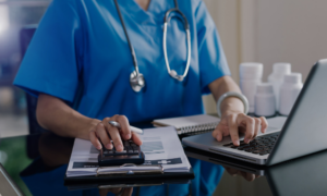 A doctor sits at a computer making notes