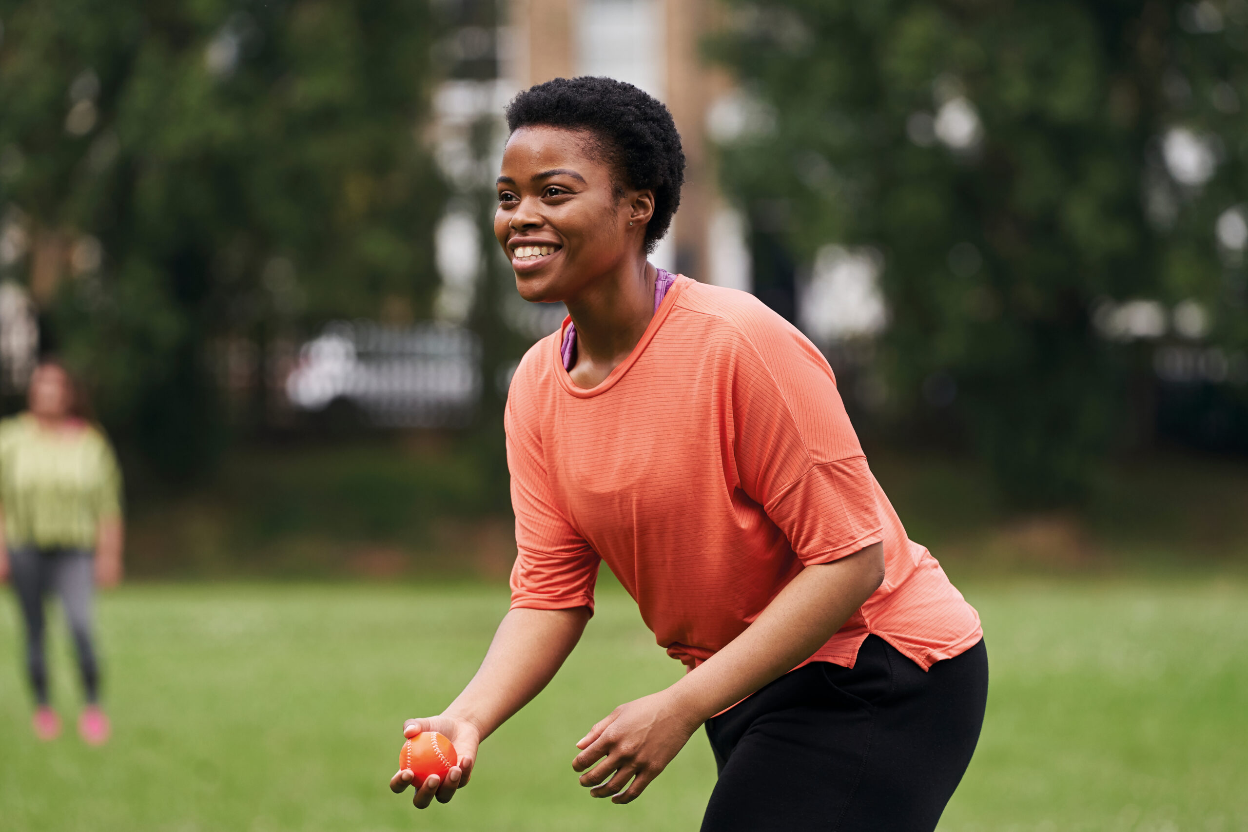 Image shows woman holding a cricket ball.