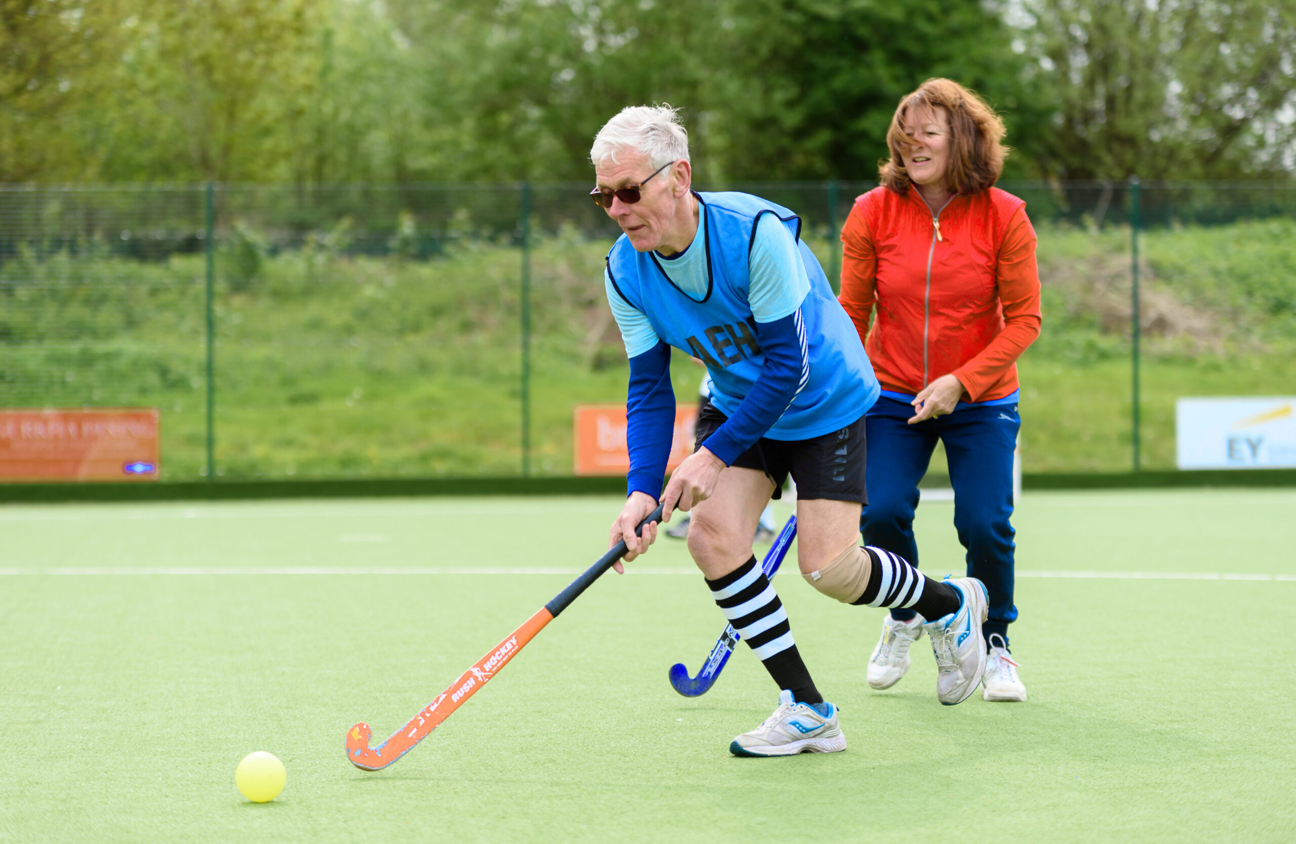 Image shows man and woman playing hockey.