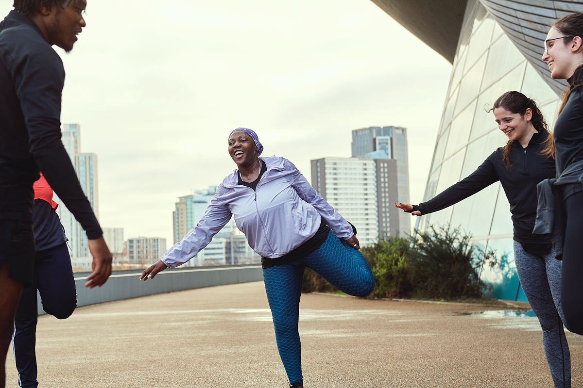 Image shows group of women outside stretching.