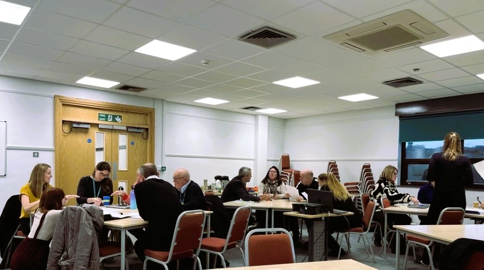 Image shows partners sat around tables for group discussions.