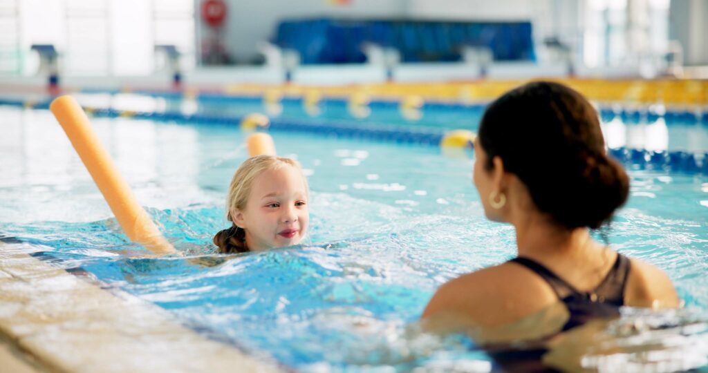 Image shows young child being taught how to swim