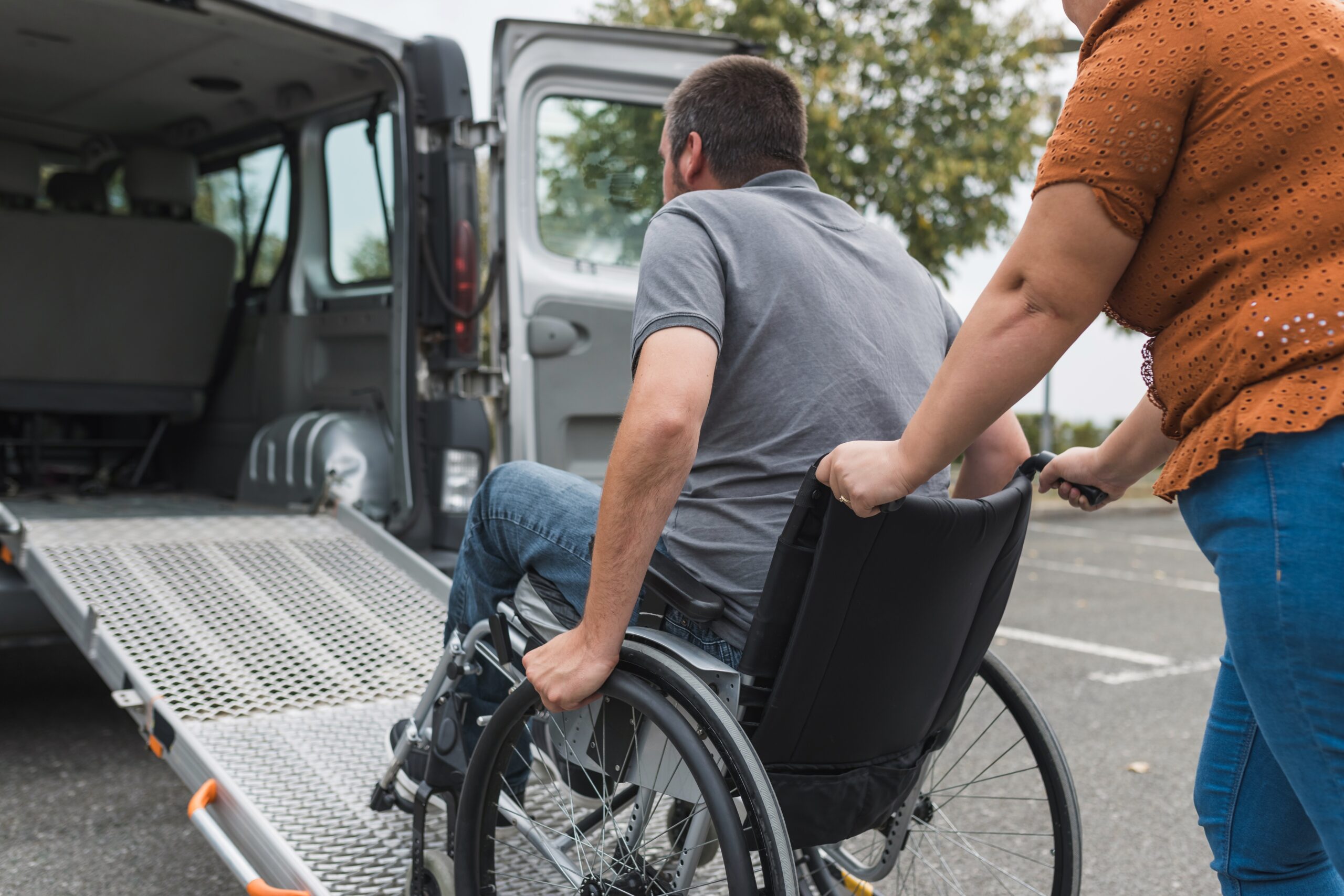 Image shows wheelchair user being assisted on a ramp into a vehicle